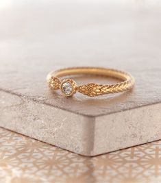 a gold ring sitting on top of a white box with a diamond in the middle