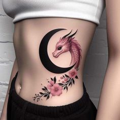 a woman's stomach with a dragon and crescent tattoo on the side, which has flowers