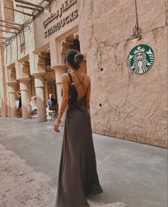 a woman standing in front of a starbucks building with her back turned to the camera