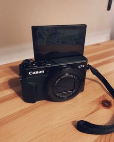 a camera sitting on top of a wooden table next to a black bag and strap