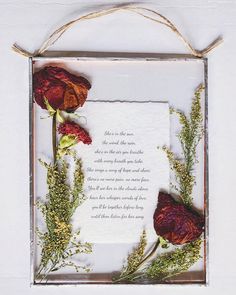 a piece of paper with flowers on it and a poem written in the middle, hanging from a rope