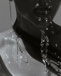 a black and white photo of a woman's face with water coming out of her mouth