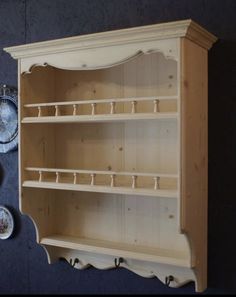 a wooden shelf on the wall with plates and bowls hanging from it's sides