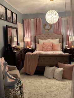 a bedroom decorated in pink and gray with a chandelier hanging from the ceiling