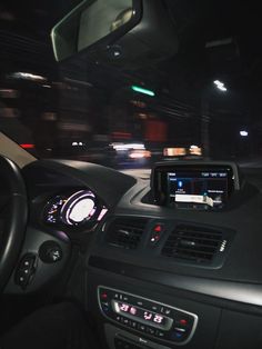 the dashboard of a car at night, with lights on and cars driving in the background