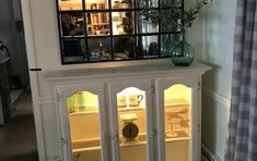 a white china cabinet with glass doors on the top and bottom, in a living room