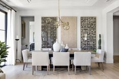 a dining room table with white chairs and art on the wall