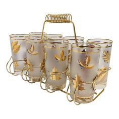 a set of six glass cups with gold leaves on the rims and wire holder