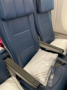 an airplane seat with two pillows and one pillow on the back, in front of it