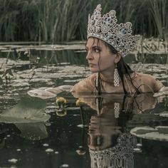 a woman wearing a tiara floating on top of a body of water with lily pads