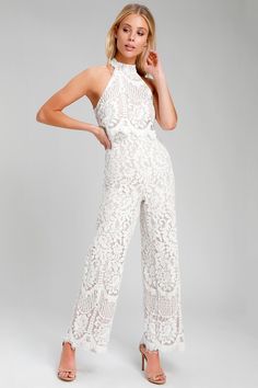 a woman in white lace jumpsuits posing for the camera with her hand on her hip