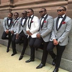 a group of men in suits and sunglasses sitting next to each other near a wall