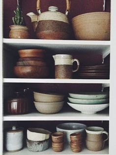 the shelves are filled with dishes and pots