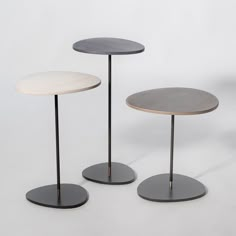 three round tables with black bases and white tops, one on top of the other