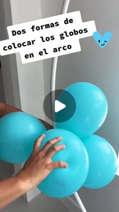 a person holding blue balloons in front of a white wall with words on it that say do formas de color los globos en el arco