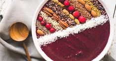 a large bowl filled with food on top of a white table next to a wooden spoon