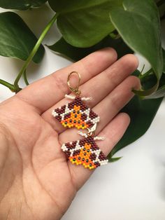 a hand holding two small beaded earrings