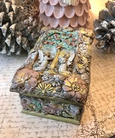 a decorative box sitting on top of a table next to pine cones