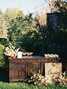 an old wooden table with flowers and candles on it in the middle of some grass