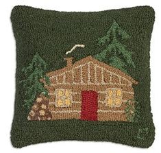 a green pillow with a small house on the front and trees in the back ground