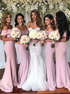 a group of women standing next to each other in front of a flower covered wall