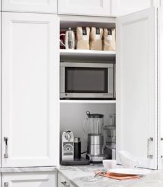 an open cabinet in the kitchen with coffee bags on it and a toaster oven