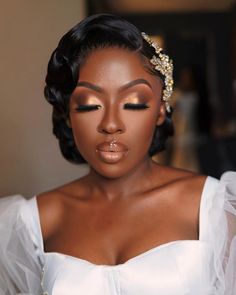 a woman wearing a white dress and gold headpiece with pearls on her hair is looking at the camera