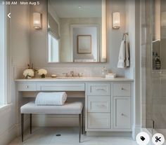 a white bathroom with two sinks and a large mirror above the sink, along with a bench in front of it