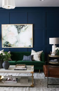 a living room with blue walls and green couches in front of a painting on the wall