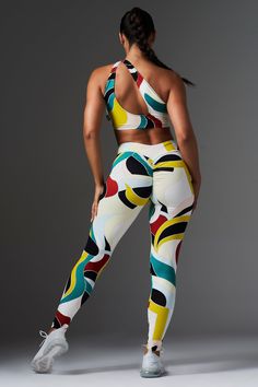 a woman in colorful sports bra top and leggings with her back to the camera