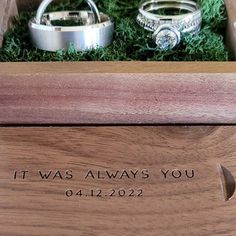 two wedding rings sitting in a wooden box with the words it was always you engraved on them