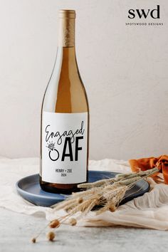 a bottle of wine sitting on top of a blue plate next to some dried flowers