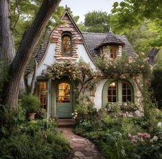 a small house with lots of flowers growing on it's roof and windows in the front