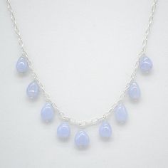 "SIMPLE The SIMPLE line is just that. It allows emphasis on the gems themselves. Here are beautiful blue, tear drop chalcedony, ~8mm x 10mm. And at the clasp is a 3mm round Moonstone. The chain is a sterling silver open loop chain which is 21\" and adjustable to 18\". Stacking these necklaces is simple too and the adjustable length means you can stack them in any order. The small moonstone at the clasp means that with the 18\" length you have a tiny gem hanging down your back. All items in the SIMPLE line are sold separately but if you would like to pair them -- necklace and earring -- the set price would be $100." Silver Teardrop Gemstone Beaded Necklace, Chalcedony Gemstone Necklace With Round Beads, Blue Faceted Round Bead Necklaces, Blue Moonstone Teardrop Necklace, Blue Moonstone Round Bead Necklaces, Blue Chalcedony Round Beads Necklace, Blue Chalcedony Dangle Jewelry, Nickel-free Light Blue Round Bead Jewelry, Chain Loop