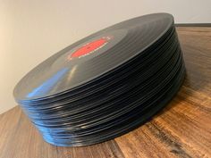 a stack of black records sitting on top of a wooden table