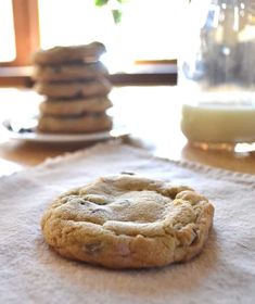 a cookie sitting on top of a table next to a glass of milk and some cookies