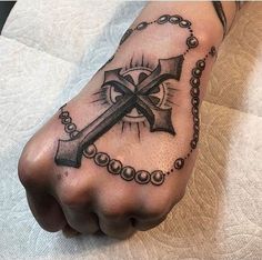 a foot with a cross and rosary tattoo on it