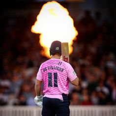 a man holding a bat in his hand while standing next to a ball on fire