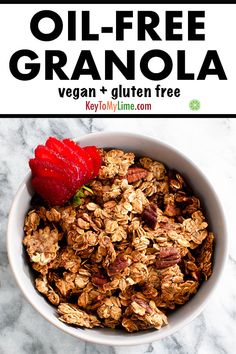 a bowl filled with granola next to a strawberry on top of a marble counter