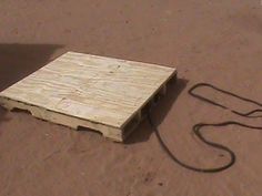 a piece of wood laying on the ground next to a cord and an object in the sand