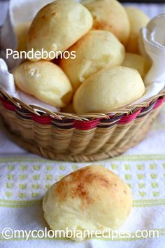 bread rolls in a basket on top of a table cloth next to a bowl of buns