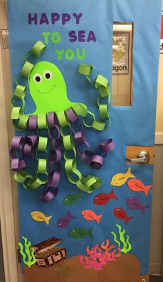 a door decorated with paper cutouts and an octopus in the ocean, says happy to sea you