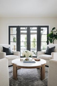 a living room filled with white furniture and flowers on top of a round coffee table