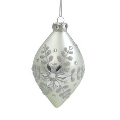 a glass ornament with silver and white decorations hanging from a wire on a white background