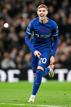 a soccer player is running on the field with his mouth open and one foot in the air