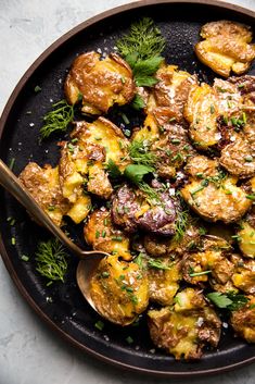 a pan filled with potatoes covered in sauce and garnished with fresh parsley