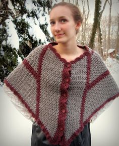 a woman standing in the snow wearing a crocheted shawl with buttons on it