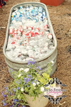 an old metal tub filled with water and plastic bottles sitting on top of dry grass