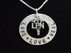 "Licensed Practical Nurse A new accessory staple for your favorite LPN - or even for yourself. It features a handcrafted fine silver circle that is hand stamped with Live Love Heal and has an LPN caduceus charm that lays over the circle. The circle measures approx 1 1/8\" and comes on your choice of 16\", 18\" or 20\" sterling silver box chain. Additional nurse designs can be found in the \"Professions\" section of my shop: https://www.etsy.com/shop/silverdragonfly260?section_id=7791707&ref= Symbolic Hand Stamped Sterling Silver Jewelry, Nickel-free Open Circle Jewelry Gift, Inspirational Hand Stamped Silver Jewelry, Meaningful Silver Jewelry Stamped 925, Meaningful Silver 925 Stamped Jewelry, Inspirational Handmade Sterling Silver Jewelry, Handmade Inspirational Sterling Silver Jewelry, Inspirational Silver Round Pendant Jewelry, Stamped Sterling Silver Jewelry For Valentine's Day