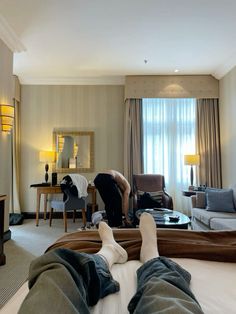 a person laying on top of a bed next to a living room filled with furniture